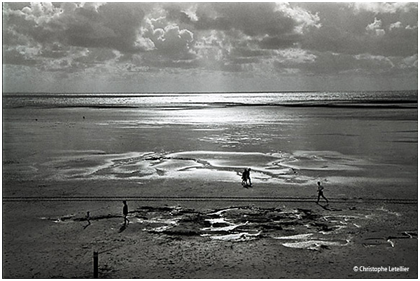 Photo noir et blanc de la galerie "Entre ciel et terre". Rayons lumineux du soleil filtrés par les nuages sur la plage de Kairon (Manche) à marée basse. © Août 2001 Christophe Letellier, tous droits réservés. Pour revenir à la galerie, cliquez sur la photo.